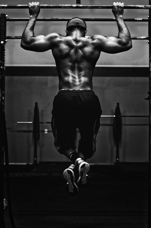 man doing pull-ups in a sports gym. Photo by Edgar Chaparro on Unsplash