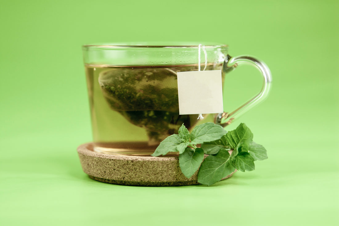 glass with green tea bag and green background Photo by Laårk Boshoff on Unsplash